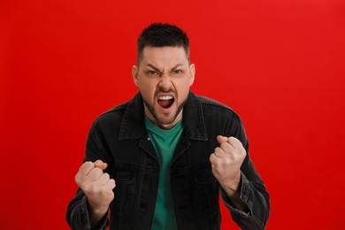 Photo of Angry man yelling on red background. Hate concept