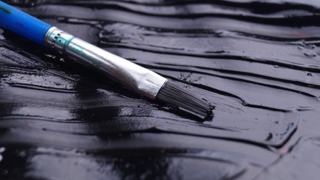 Photo of Brush on artist's palette with black paint, closeup