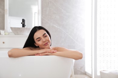 Beautiful young woman relaxing in bathtub at home