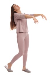 Young woman wearing pajamas and slippers in sleepwalking state on white background