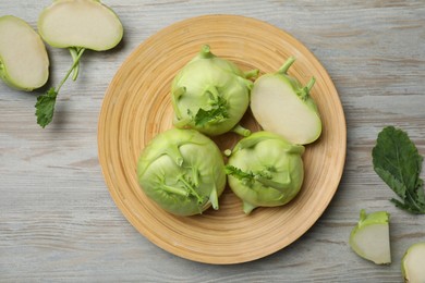 Whole and cut kohlrabi plants on wooden table, flat lay