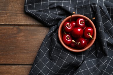Sweet red cherries in bowl on wooden table, top view. Space for text