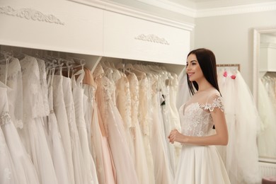 Photo of Woman trying on beautiful wedding dress in boutique