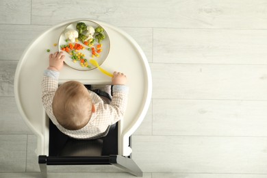 Cute little baby eating healthy food, top view. Space for text
