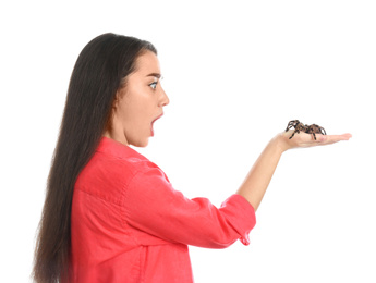 Photo of Scared young woman with tarantula on white background. Arachnophobia (fear of spiders)