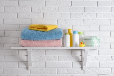 Shelf with baby accessories on white brick wall