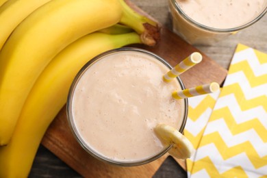 Photo of Glass with banana smoothie on wooden table, flat lay
