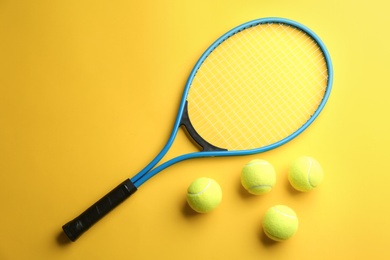 Tennis racket and balls on yellow background, flat lay. Sports equipment