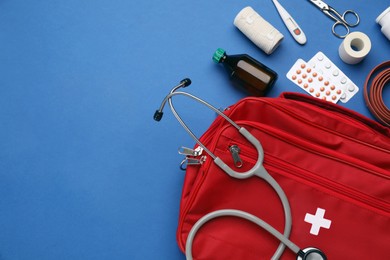 Flat lay composition with first aid kit on blue background, space for text