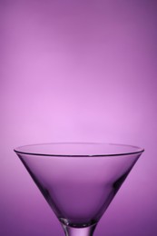 Photo of Elegant empty martini glass on purple background, closeup. Space for text