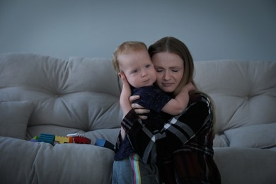 Depressed single mother hugging her child in living room