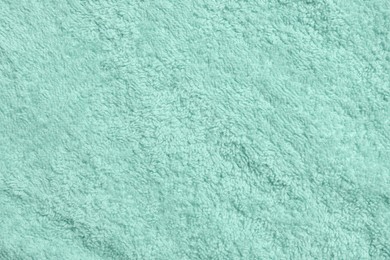 Soft light turquoise towel as background, top view