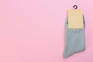 Pair of grey cotton socks on light pink background, top view. Space for text