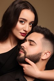 Handsome bearded man with sexy lady on brown background, closeup