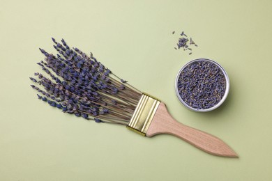 Creative flat lay composition with paint brush and lavender flowers on light green background