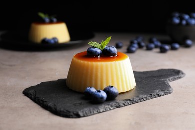 Photo of Delicious caramel pudding with blueberries and mint on grey table
