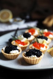Photo of Delicious tartlets with red and black caviar served on table, closeup