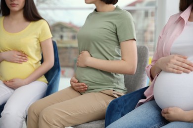 Group of pregnant women at courses for expectant mothers indoors, closeup