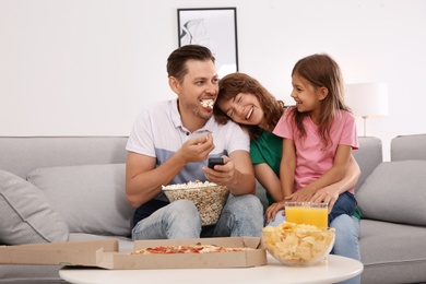 Family watching TV with popcorn in room