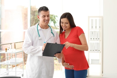 Young doctor with pregnant woman in hospital. Patient consultation