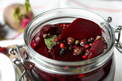 Pickled beets in glass preserving jar on table, closeup