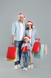 Happy family with paper bags and gift on grey background. Christmas shopping