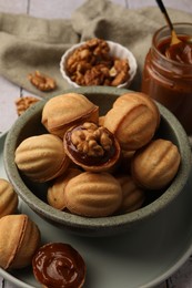 Photo of Delicious nut shaped cookies with boiled condensed milk on table, closeup