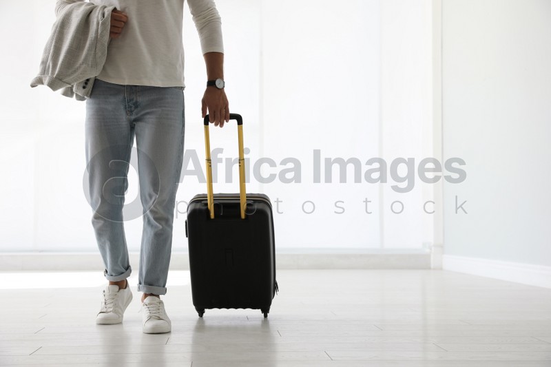 Man with black travel suitcase in airport. Space for text