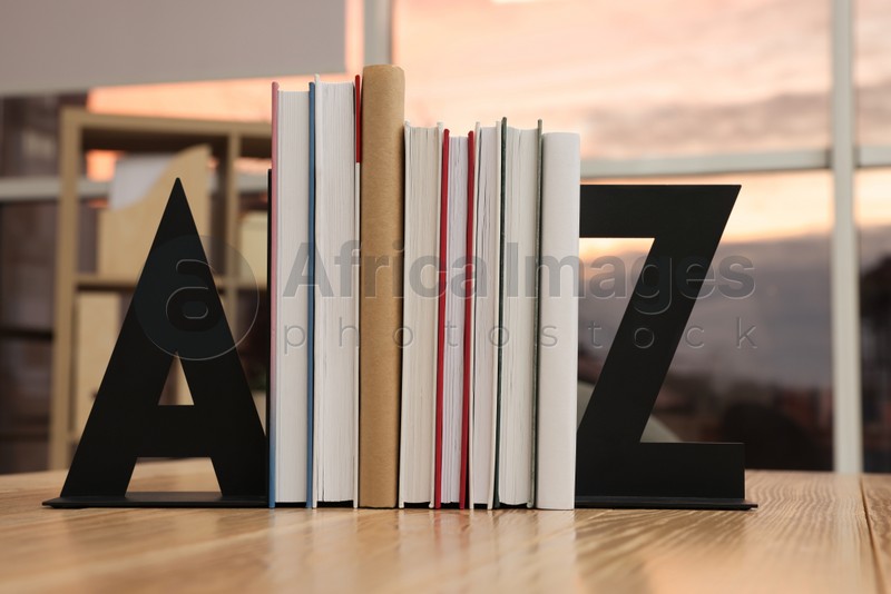 Photo of Minimalist letter bookends with books on wooden table indoors
