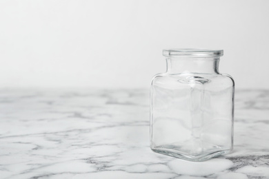 Empty glass jar on white marble table, space for text