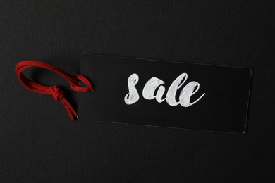 Tag with word SALE on dark background, top view. Black Friday concept