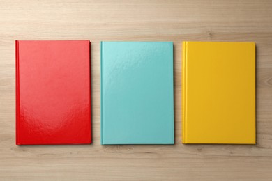 Three colorful planners on wooden table, flat lay