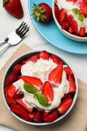 Delicious strawberries with whipped cream served on white table, flat lay