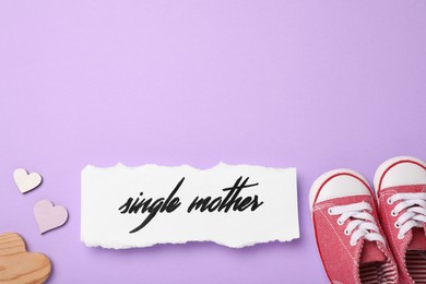 Being single mother concept. Children's gumshoes and decorative hearts on violet background, flat lay with space for text