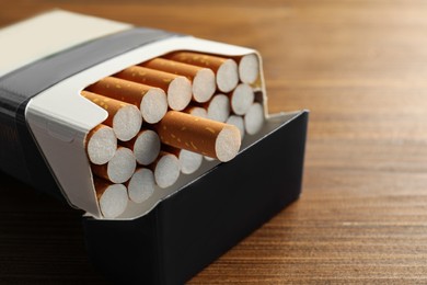 Pack of cigarettes on wooden table, closeup