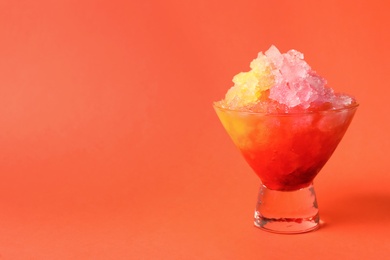 Rainbow shaving ice in glass dessert bowl on orange background, closeup. Space for text