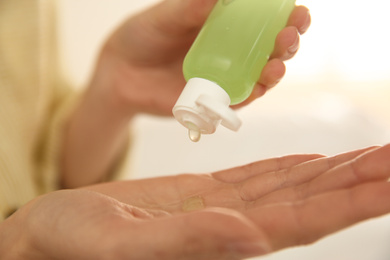 Woman applying antiseptic gel on blurred background, closeup