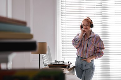 Young woman listening to music with turntable at home