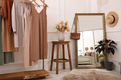 Dressing room interior with large mirror and stylish clothes