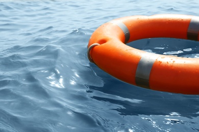 Orange life buoy floating in sea, closeup. Emergency rescue equipment