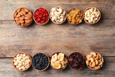 Composition of different dried fruits and nuts on wooden background, top view. Space for text