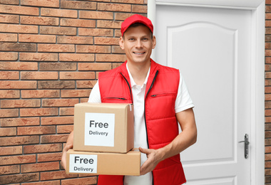 Courier holding parcels with stickers Free Delivery indoors