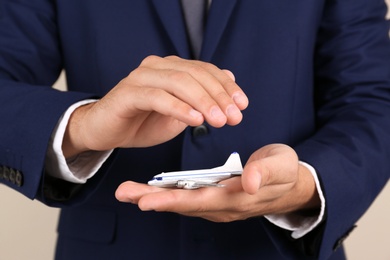 Insurance agent covering toy plane on color background, closeup. Travel safety concept