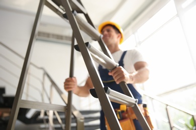 Professional builder with metal ladder on stairs, closeup