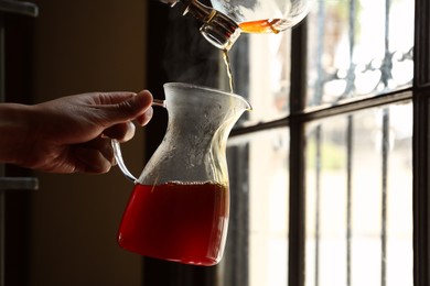 Photo of Barista pouring coffee from vacuum maker into glass jug in cafe, closeup. Space for text