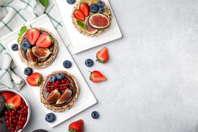 Photo of Tasty crispbreads with different toppings served on light table, flat lay. Space for text