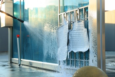 Cleaning auto mats with high pressure foam jet at car wash, closeup