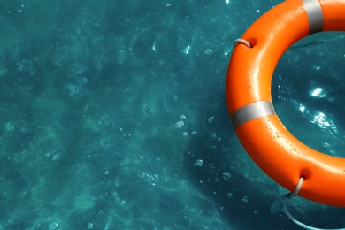 Orange life buoy floating in sea, above view. Emergency rescue equipment