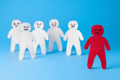 White paper figures and one red on light blue background. Bullying concept