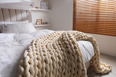 Soft chunky knit blanket on bed indoors